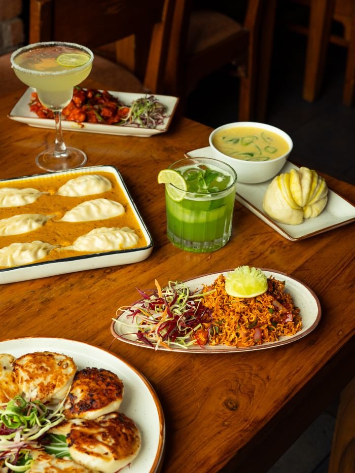 A dining table set with dumplings, spiced rice, cocktails, and soup, offering a variety of gourmet dishes.